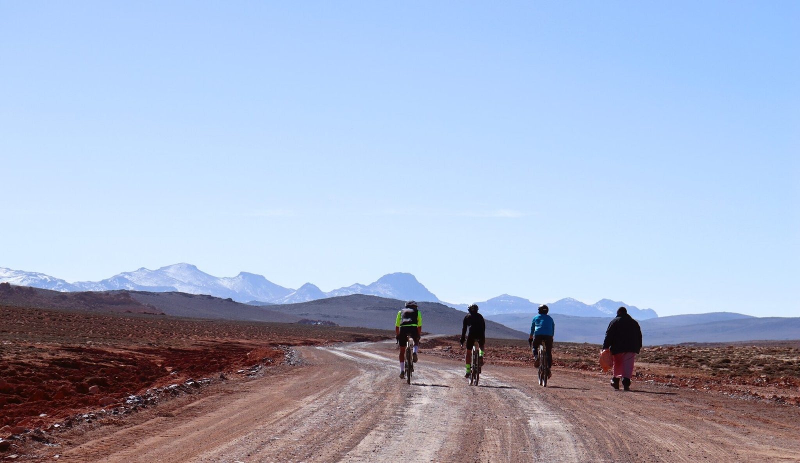 Cycling group in Morocco's High Atlas Mountains with Amazigh village and mountain scenery
